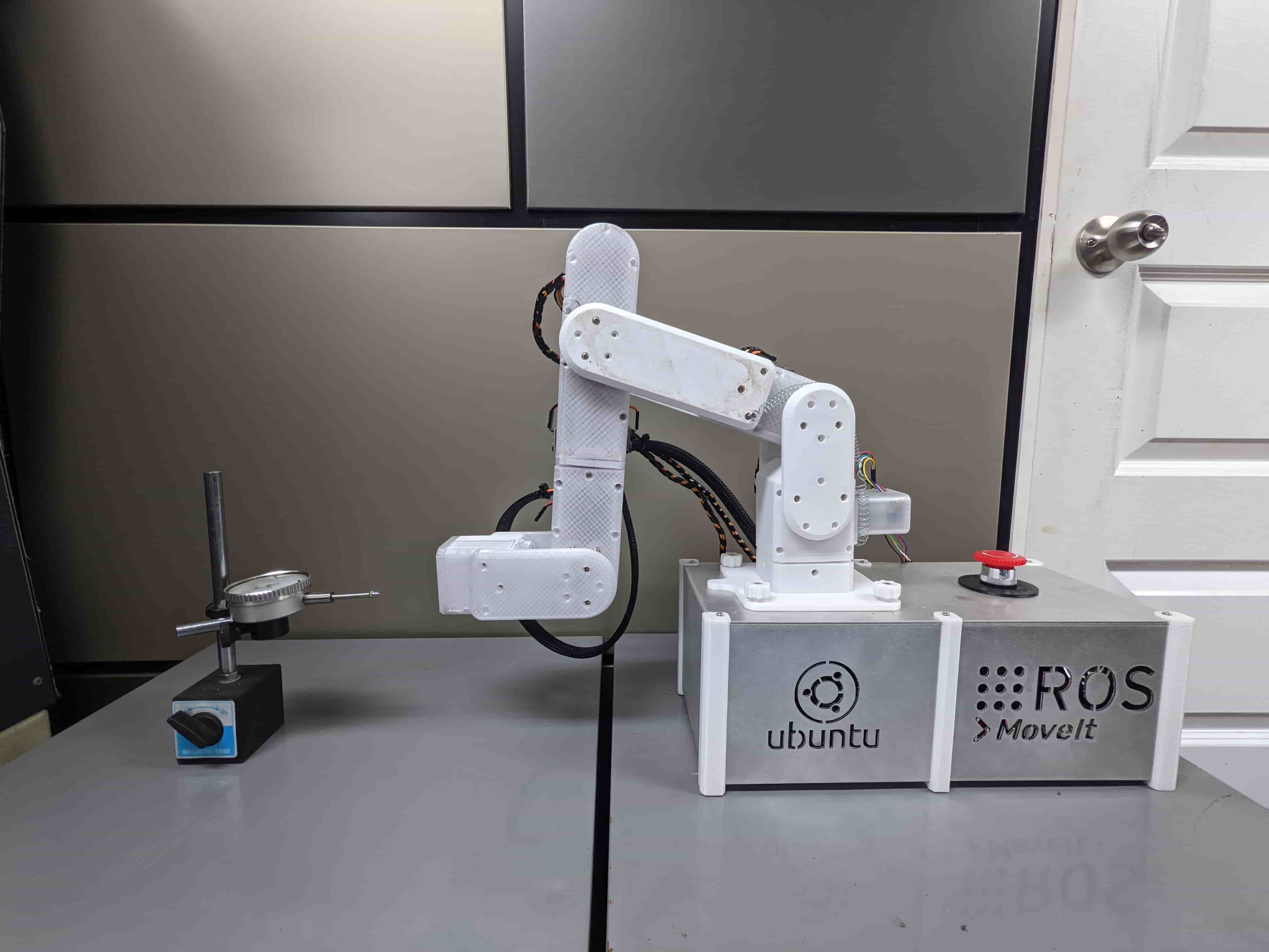 The robotic arm folded beside a dial indicator used to measure positioning performance
