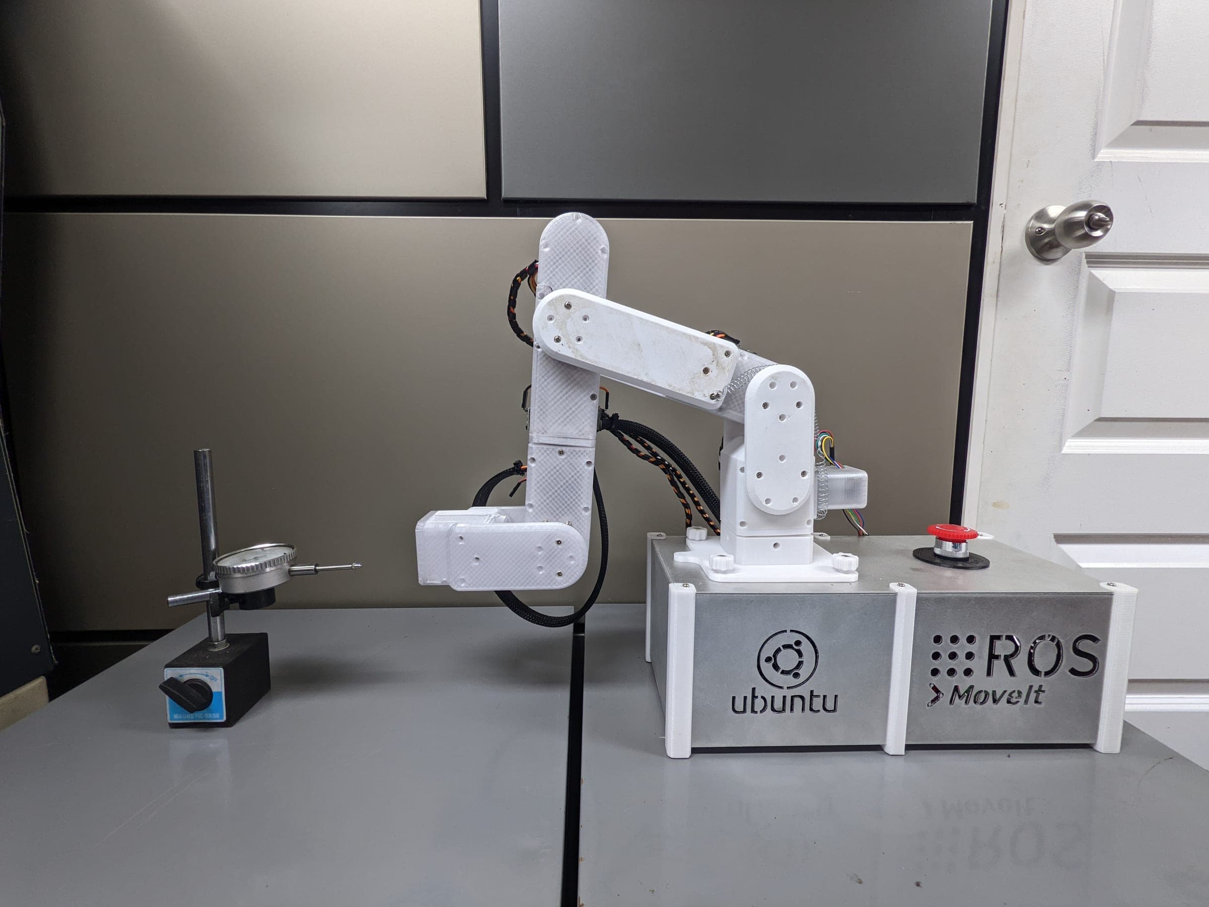The robotic arm in an extended test pose beside the dial indicator measurement frame