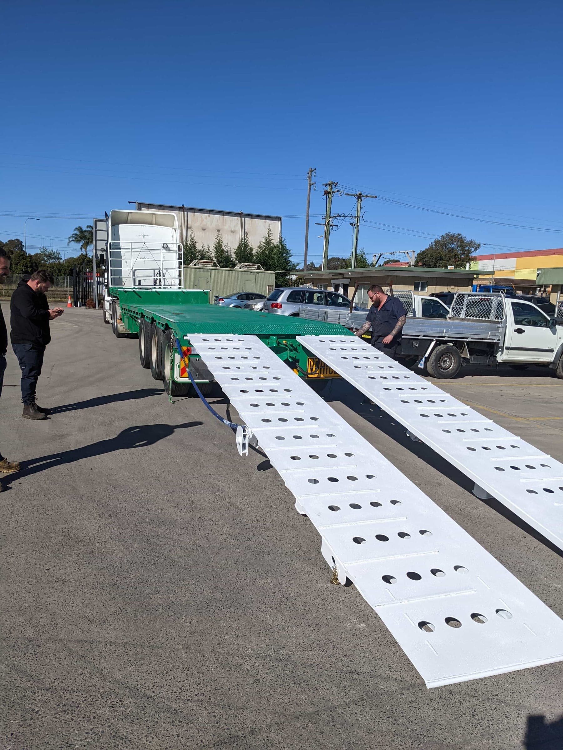 Twin truck ramps fully deployed from the rear of the transport trailer